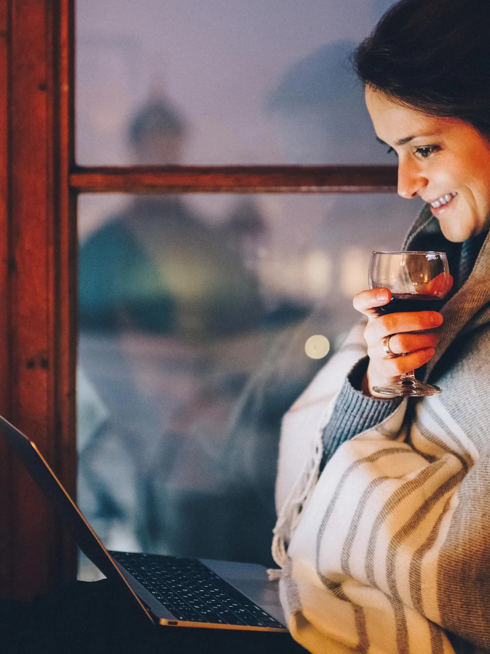 Relaxed woman at the window sill enjoying a movie on the lap top