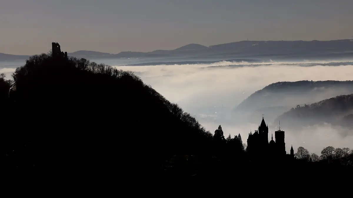 Hinter Schloss Drachenburg (r) und der Burg Drachenfels ziehen Nebelschwaden durch das Rheintal.