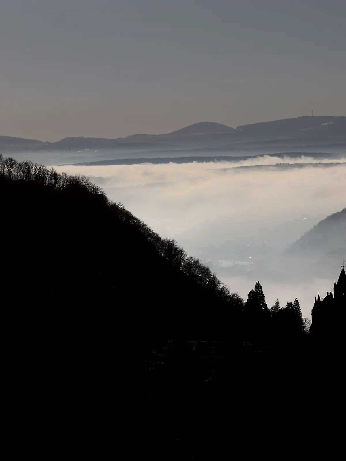 Hinter Schloss Drachenburg (r) und der Burg Drachenfels ziehen Nebelschwaden durch das Rheintal.