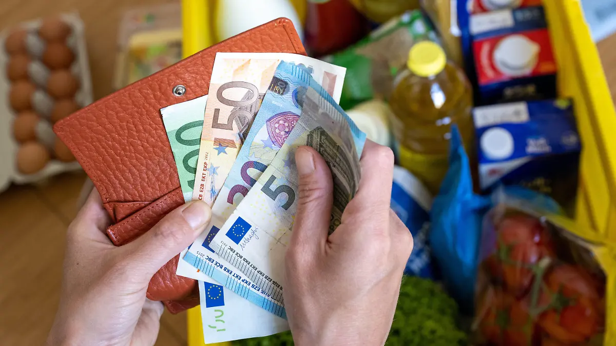 ARCHIV - 02.06.2022, Sachsen, Leipzig: Eine Einkaufskiste mit Lebensmitteln steht auf einem Küchentisch in Leipzig, während eine Frau Euro-Banknoten in den Händen hält. Wie sich die Inflation im Juli entwickelt hat, gibt das Statistische Bundesamt am Donnerstagnachmittag in einer ersten Schätzung bekannt. (zu dpa "Inflation weiter über 7 Prozent - Bundesamt gibt Juli-Daten bekannt") Foto: Hendrik Schmidt/dpa +++ dpa-Bildfunk +++