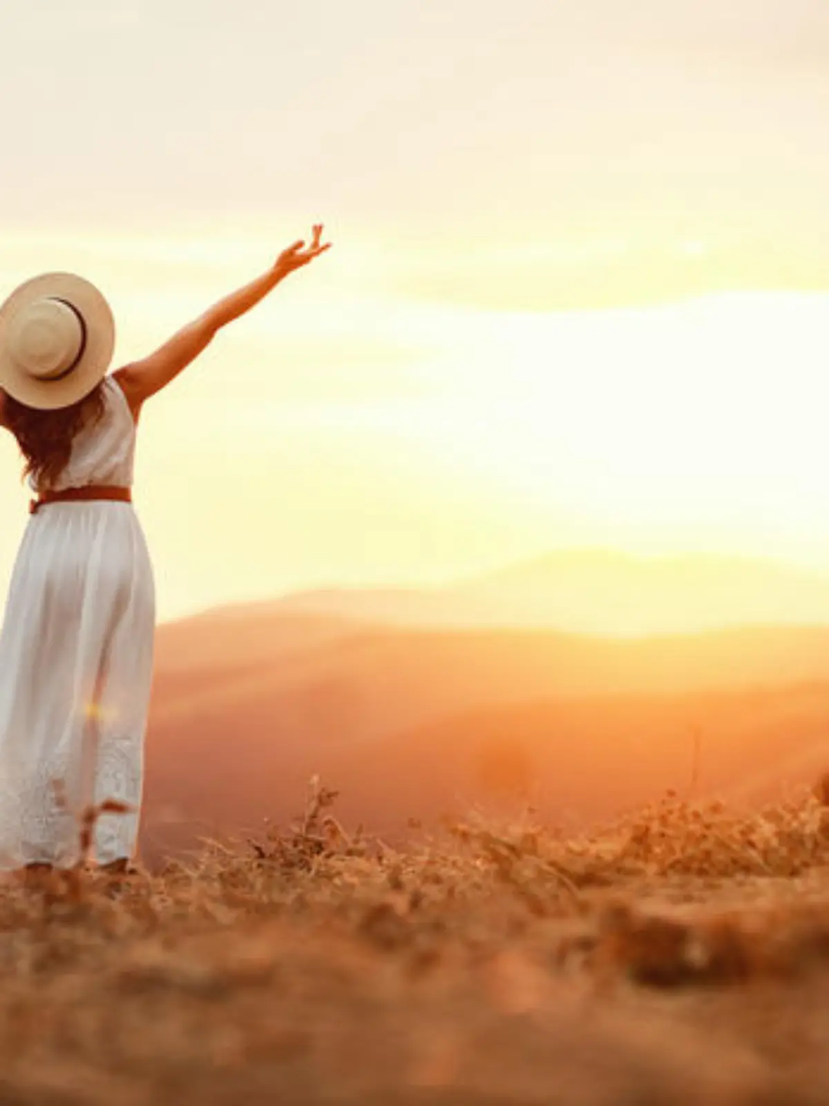 Happy woman standing with her back on the sunset in nature in summer