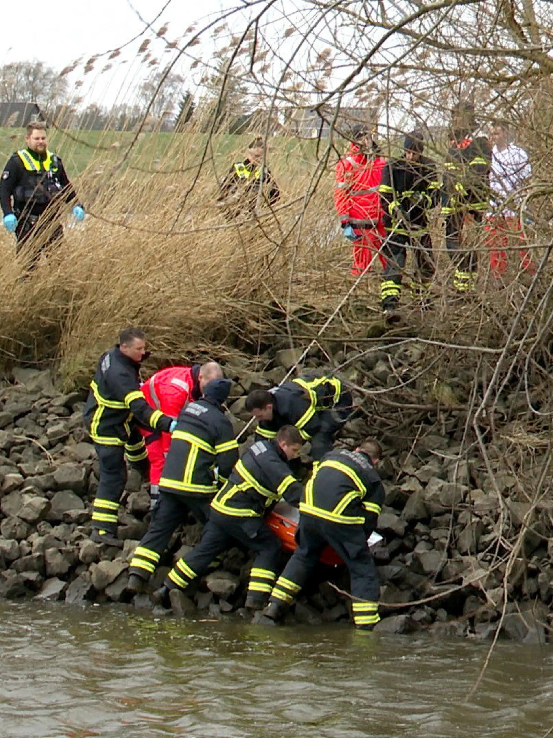 24.01.2024, Hamburg: Einsatzkräfte bergen im Stadtteil Ochsenwerder eine Leiche aus dem Uferbereich der Elbe. Der Polizei war am Vormittag eine leblos im Wasser treibende Person gemeldet worden, Angaben zu Geschlecht, Alter und den Todesumständen gab es zunächst nicht. (Zu dpa ·Leiche treibt in Norderelbe - Identität unbekannt·) Foto: Daniel Bockwoldt/dpa +++ dpa-Bildfunk +++