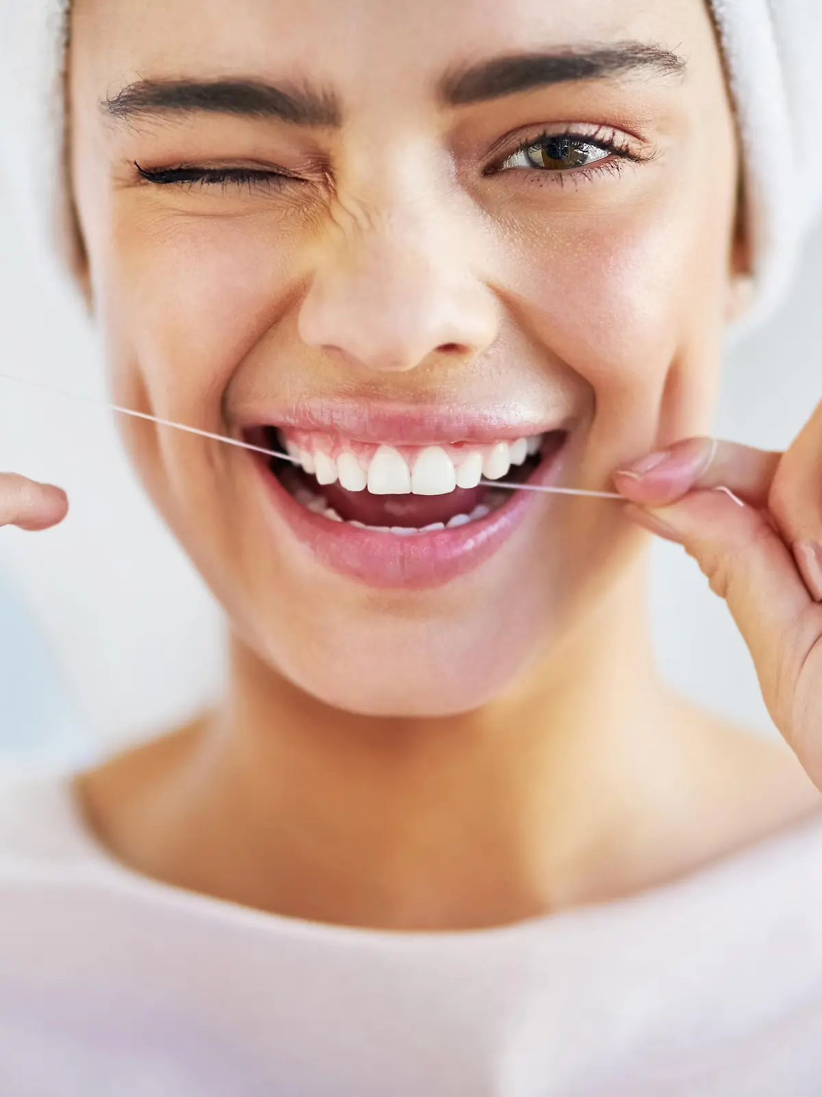Portrait of a beautiful young woman flossing her teeth in the bathroom at home