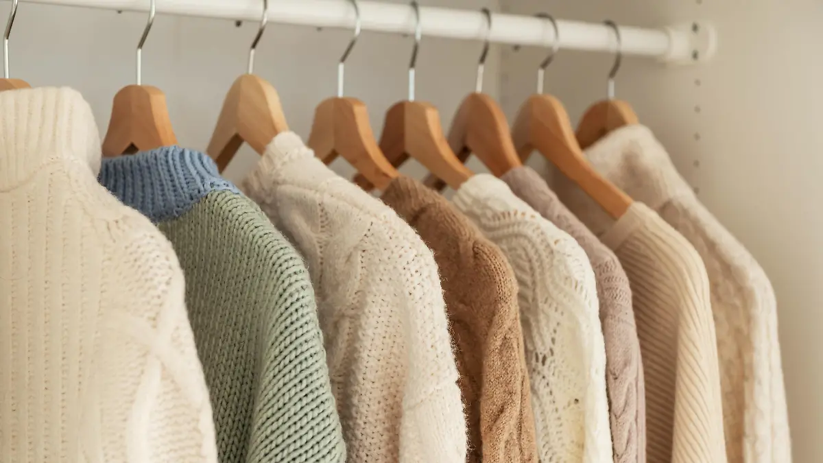 Warm winter beige wool pullover and knitwear and hanging in wardrobe