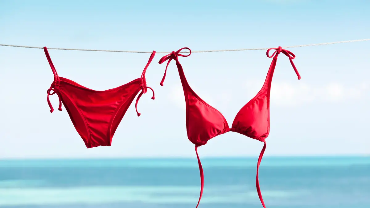 Subject: Bikini swimwear hanging on clothesline for drying, vacationing on tropical beach holiday.