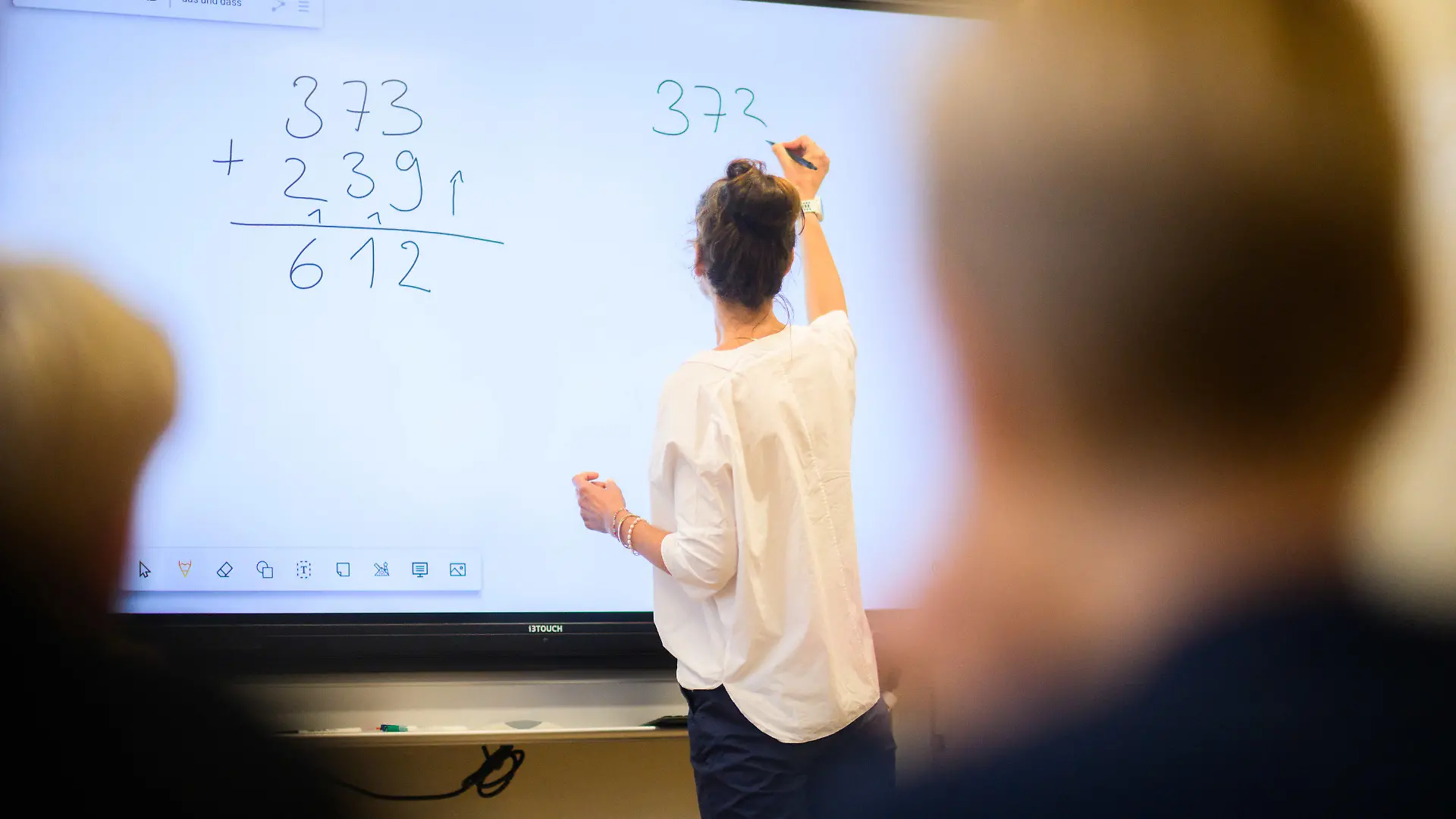 ARCHIV - 17.08.2023, Niedersachsen, Hannover: Eine Lehrerin schreibt eine Mathematikaufgabe auf eine digitale Schultafel im Klassenraum einer 4. Klasse einer Grundschule in der Region Hannover. (zu dpa "Landesrechnungshof fordert weniger Betreuungsaufgaben für Lehrkräfte") Foto: Julian Stratenschulte/dpa +++ dpa-Bildfunk +++