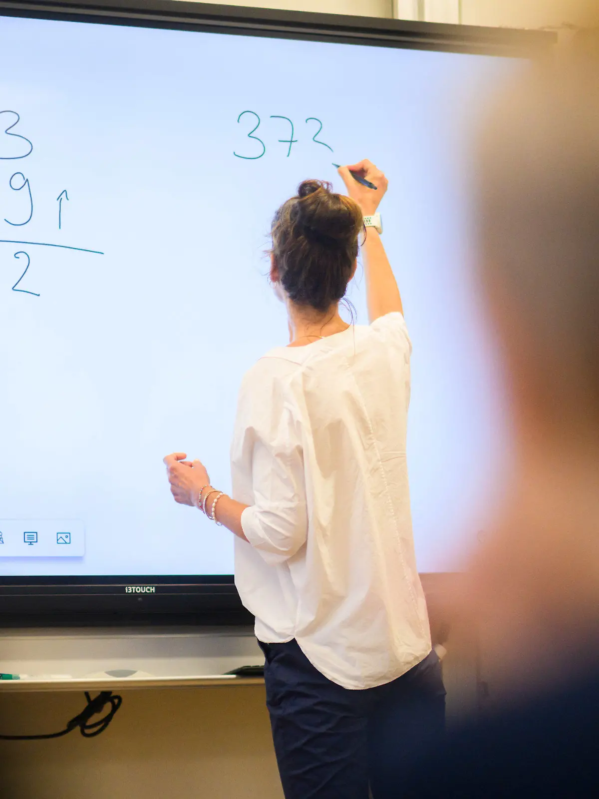 ARCHIV - 17.08.2023, Niedersachsen, Hannover: Eine Lehrerin schreibt eine Mathematikaufgabe auf eine digitale Schultafel im Klassenraum einer 4. Klasse einer Grundschule in der Region Hannover. (zu dpa "Landesrechnungshof fordert weniger Betreuungsaufgaben für Lehrkräfte") Foto: Julian Stratenschulte/dpa +++ dpa-Bildfunk +++