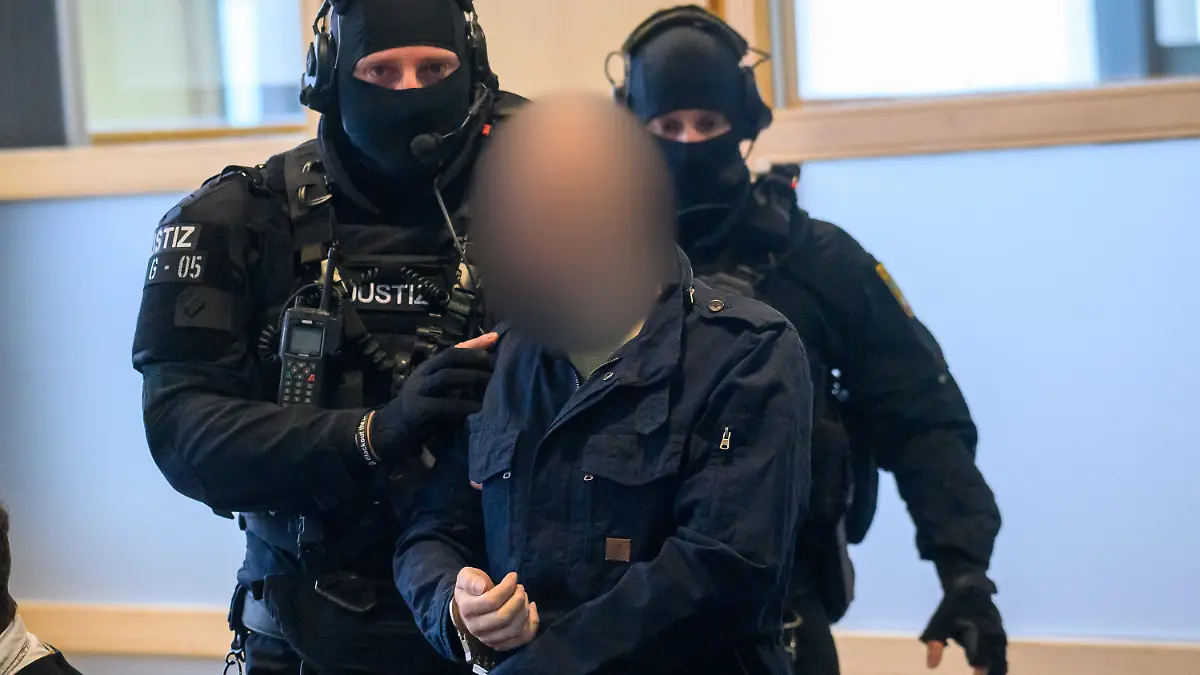 25.01.2024, Sachsen-Anhalt, Magdeburg: Justitzbeamte führen den Angeklagten Stephan Balliet in den Gerichtssaal. Dort begann am Morgen der Prozess gegen ihn. Der Angeklagte der wegen des Halle-Attentats im Gefängnis sitzt soll dort Wärter als Geiseln genommen haben. Foto: Klaus-Dietmar Gabbert/dpa - ACHTUNG: Der Angeklagte wurde auf Anweisung des Gerichts hin gepixelt +++ dpa-Bildfunk +++