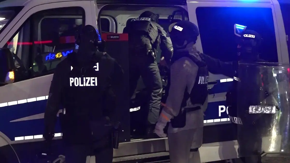 Polizeibeamte stehen vor einem Polizeiwagen.