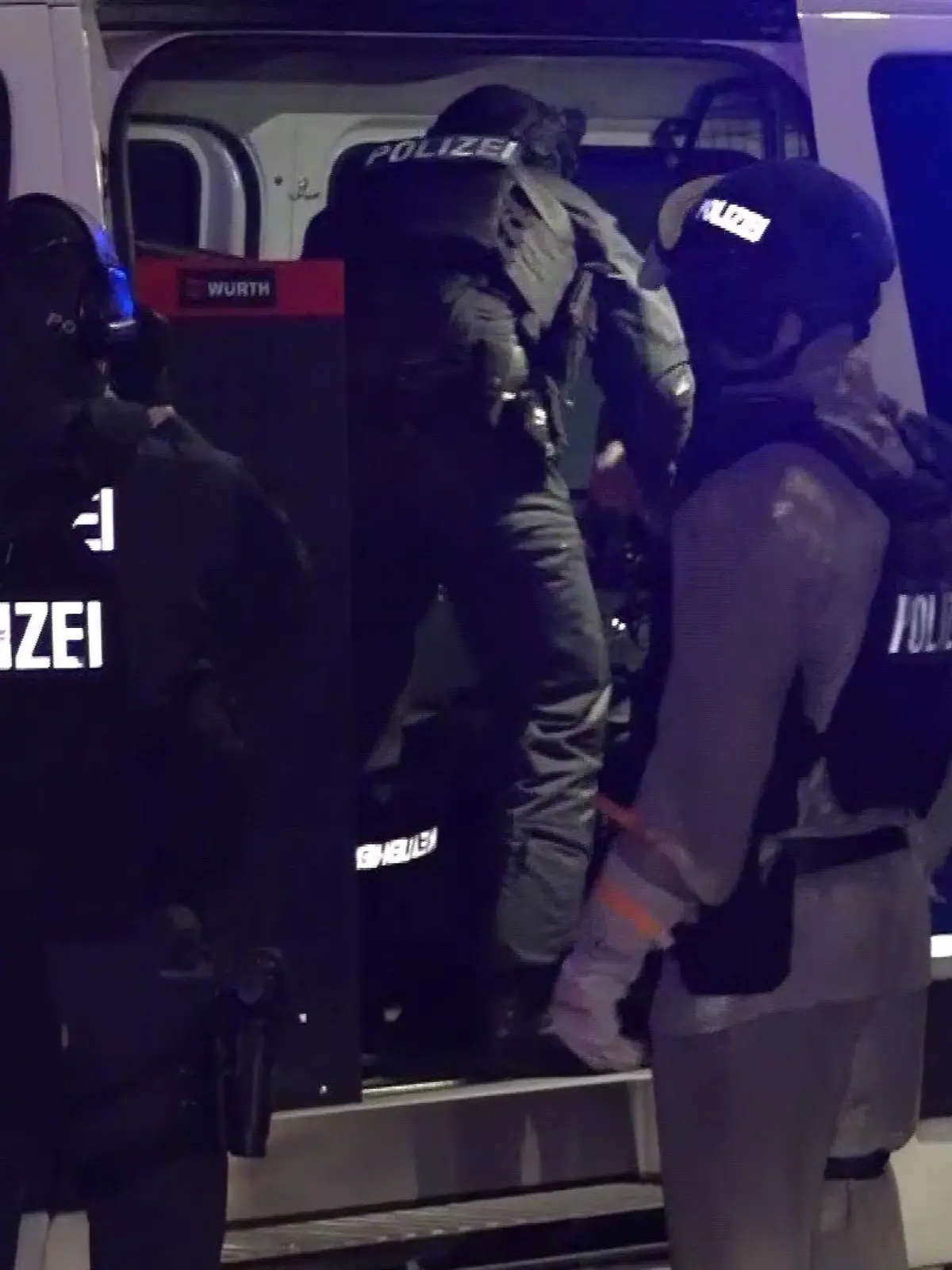 Polizeibeamte stehen vor einem Polizeiwagen.