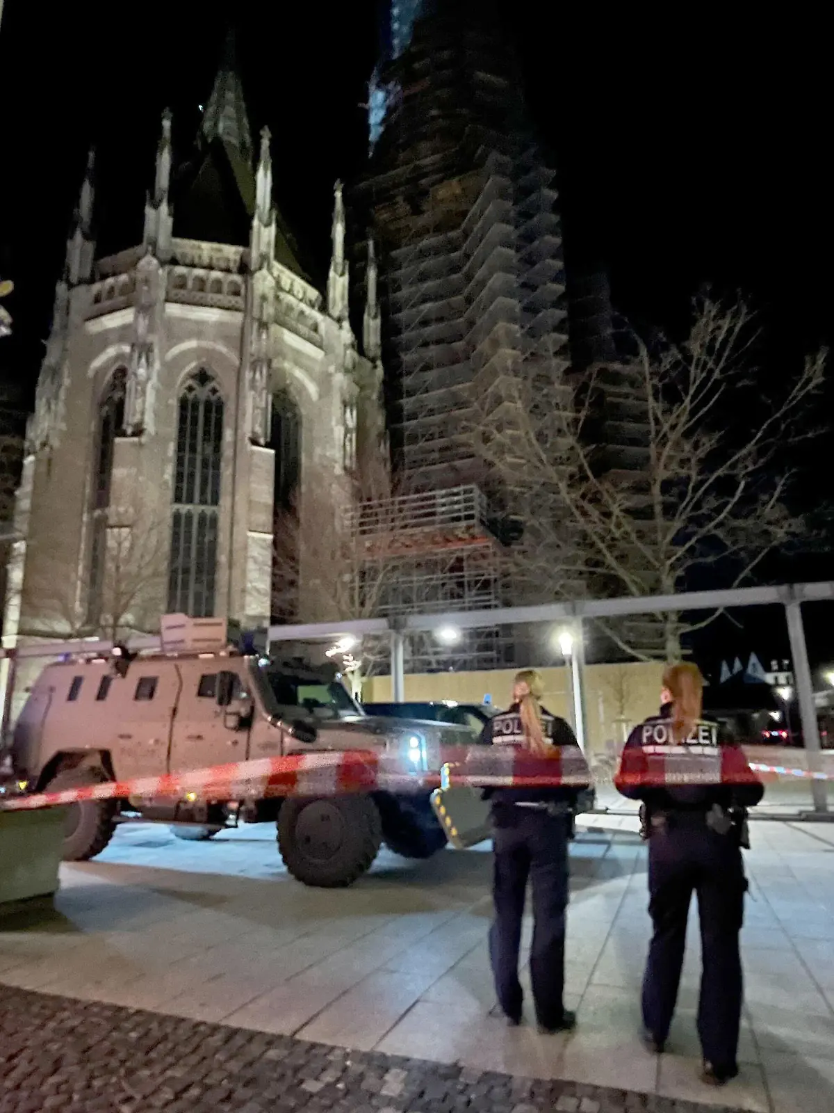 26.01.2024, Baden-Württemberg, Ulm: Zwei Polizistinnen stehen hinter einem Absperrband der Polizei am Münsterplatz. Die Polizei hat wegen eines Einsatzes am Freitagabend Teile des zentralen Münsterplatzes in Ulm gesperrt. Foto: Nico Pointner/dpa +++ dpa-Bildfunk +++
