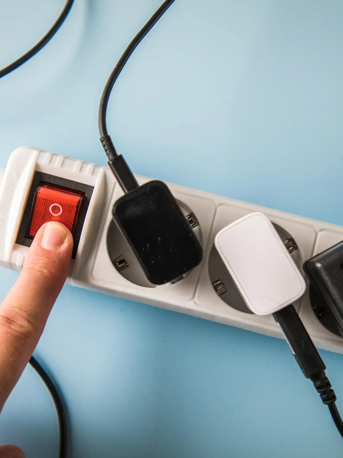 ILLUSTRATION - Eine Frau bedient am 19.07.2022 in Wittenberge den Sicherheitsschalter einer Mehrfachsteckerleiste, an der verschiedene elektrische Verbraucher angeschlossen sind (gestellte Szene). Foto: Christin Klose