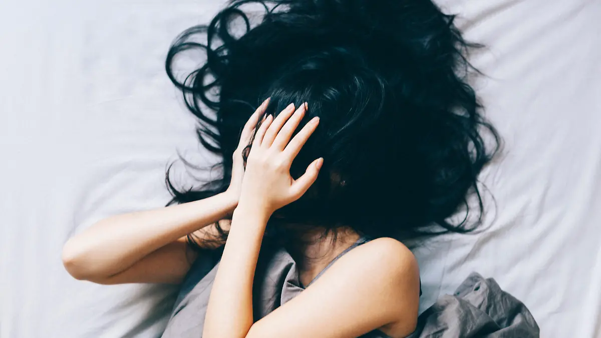 Young woman covering her face with hair and hands.