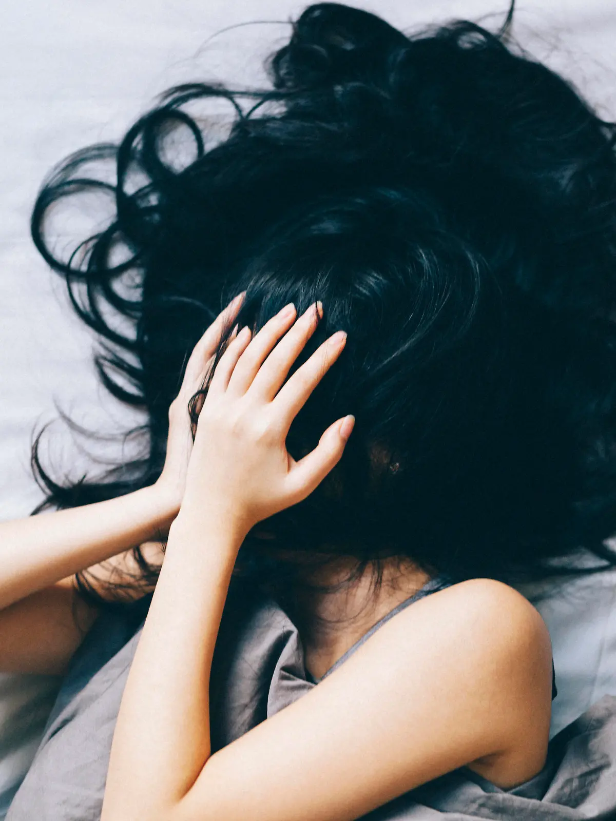 Young woman covering her face with hair and hands.