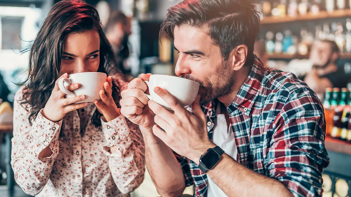 Beautiful young couple drinking coffee and looking each other