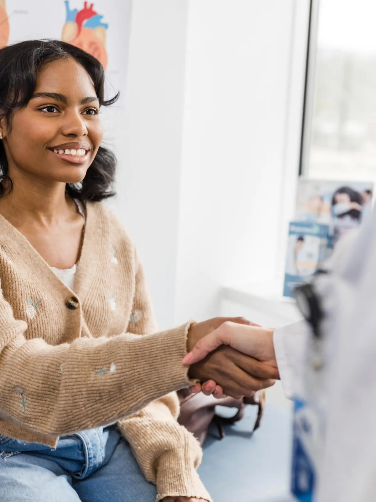 When the unrecognizable doctor walks in, the smiling young adult woman reaches out to shake hands.