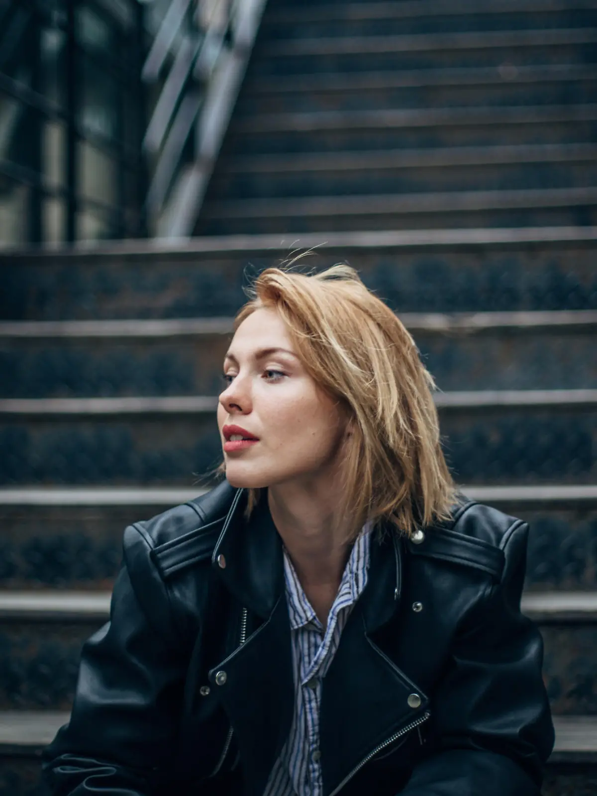 One woman, sitting outdoors on steps alone.
