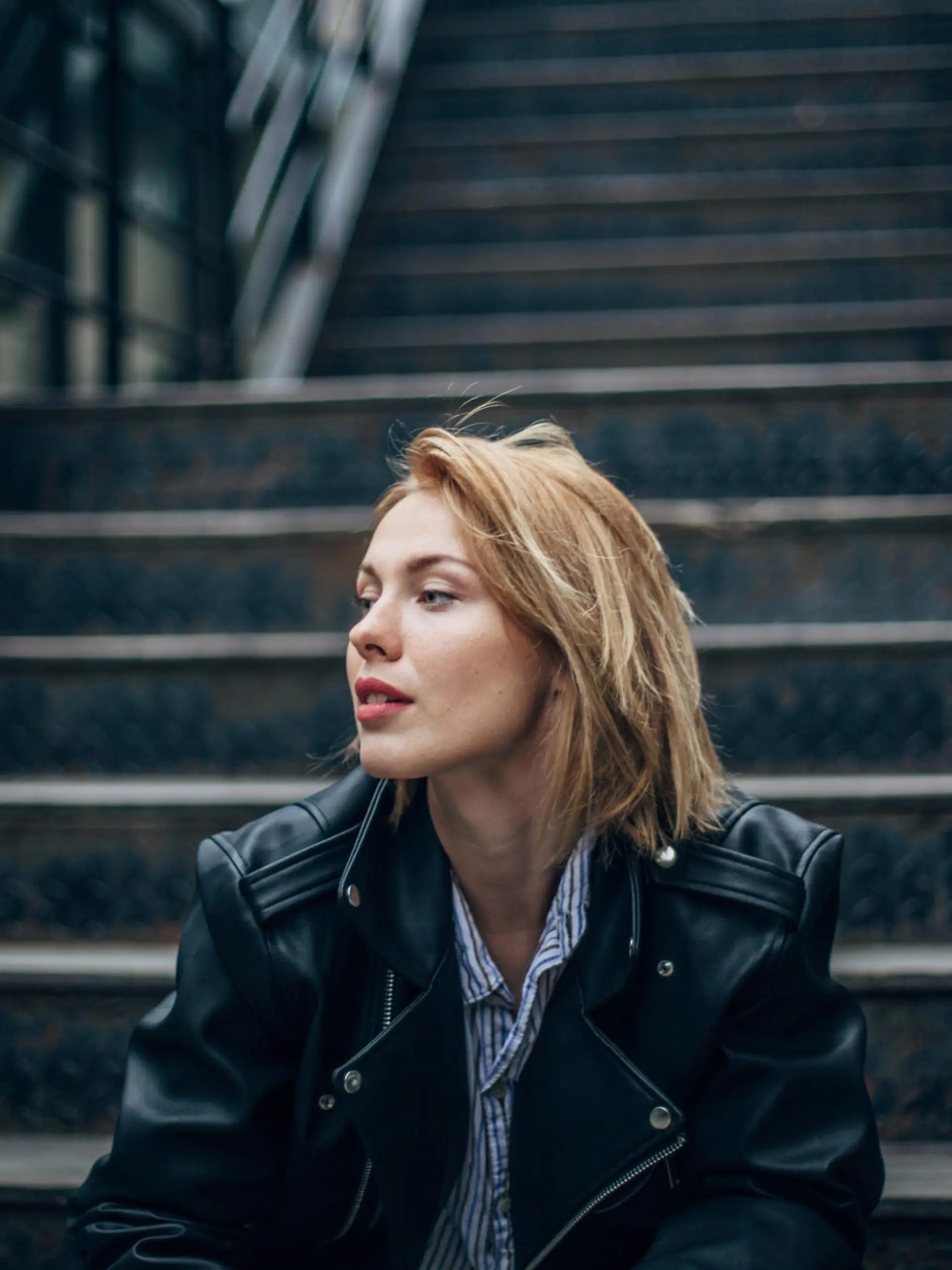 One woman, sitting outdoors on steps alone.