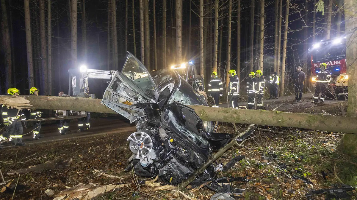 29.01.2024, Österreich, Aurolzmünster: Feuerwehrleute stehen um ein Auto herum, das von einem Baumstamm durchbohrt im Wald liegt. Bei einem Verkehrsunfall in Österreich ist das Auto einer Lenkerin von einem Baum gepfählt worden. Die 27-jährige Frau überlebte jedoch und konnte sich selbstständig aus ihrem Fahrzeug befreien, wie die Polizei am Dienstag mitteilte. Die Frau war am Vorabend bei Weilbach in Oberösterreich in einem Wald von der Straße abgekommen. Foto: Daniel Scharinger/APA/dpa +++ dpa-Bildfunk +++