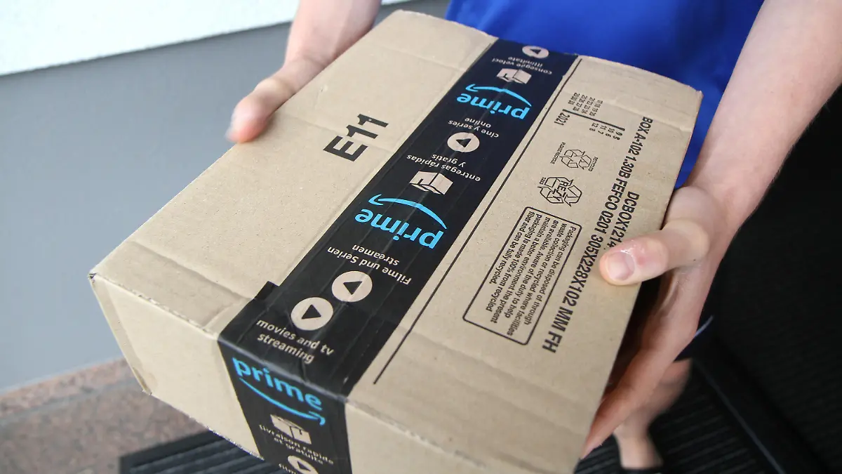 Themenbild - Paketzustellung, Paketanlieferung Amazon Prime, Prime, Logo Bild: Eine Person hat ein Paket von Amazon Prime in der Hand das vor der Haustür zugestellt wird. Themenbild, Featurebild, Symbolbild