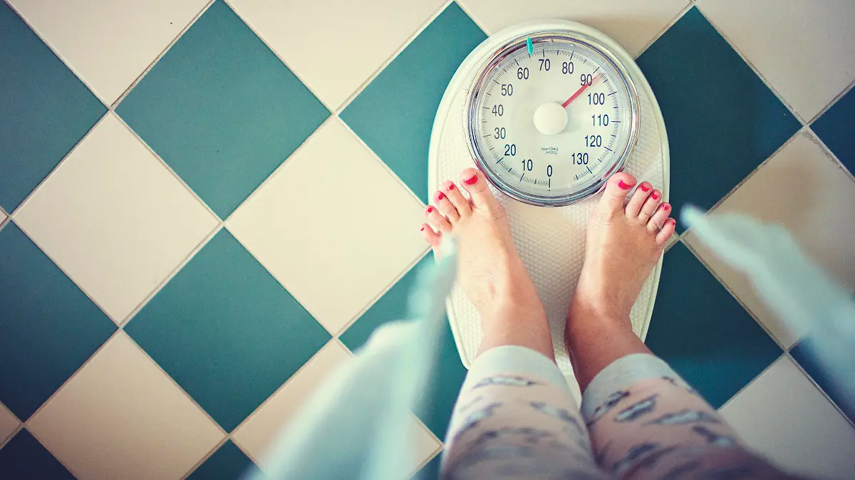 Woman stands in the bathroom on the scales in the morning