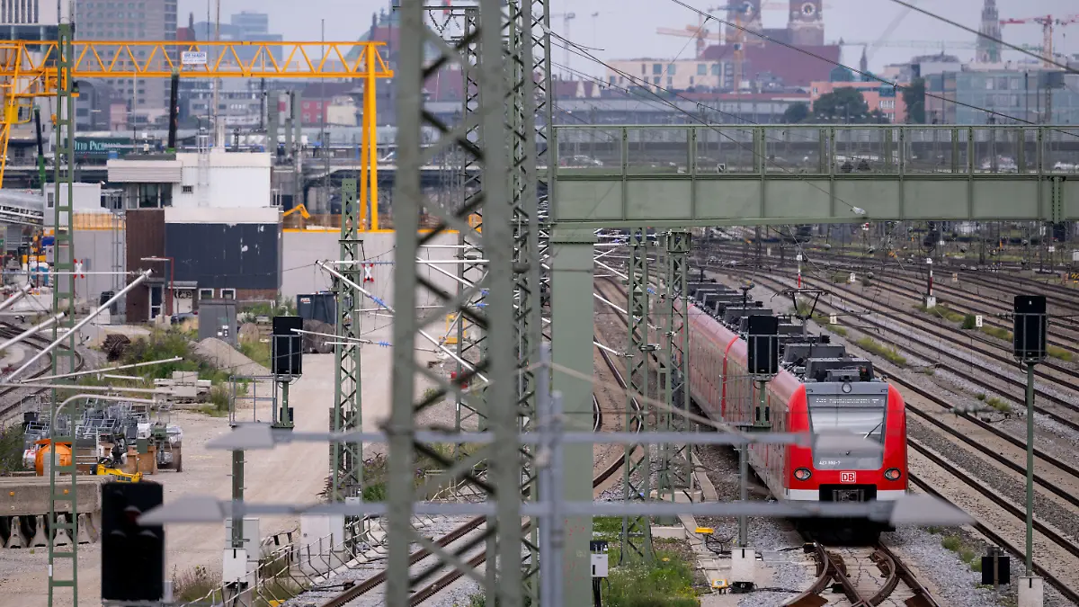 ARCHIV - 21.07.2022, Bayern, München: Ein Zug der S-Bahn München fährt an der Baustelle der zweiten S-Bahn-Stammstrecke entlang. Was nach Industrieromantik aussieht mit den Türmen der Münchner Frauenkirche im Hintergrund sorgt für heftige Debatten wegen massiver Kostensteigerungen und jahrelanger Verzögerungen. Nun hofft man in München, dass die Deutsche Bahn endlich konkrete Zahlen und Daten nennt. (zu dpa «Hoffen auf konkrete Zahlen: Die zweite S-Bahn-Stammstrecke in München») Foto: Sven Hoppe/dpa +++ dpa-Bildfunk +++