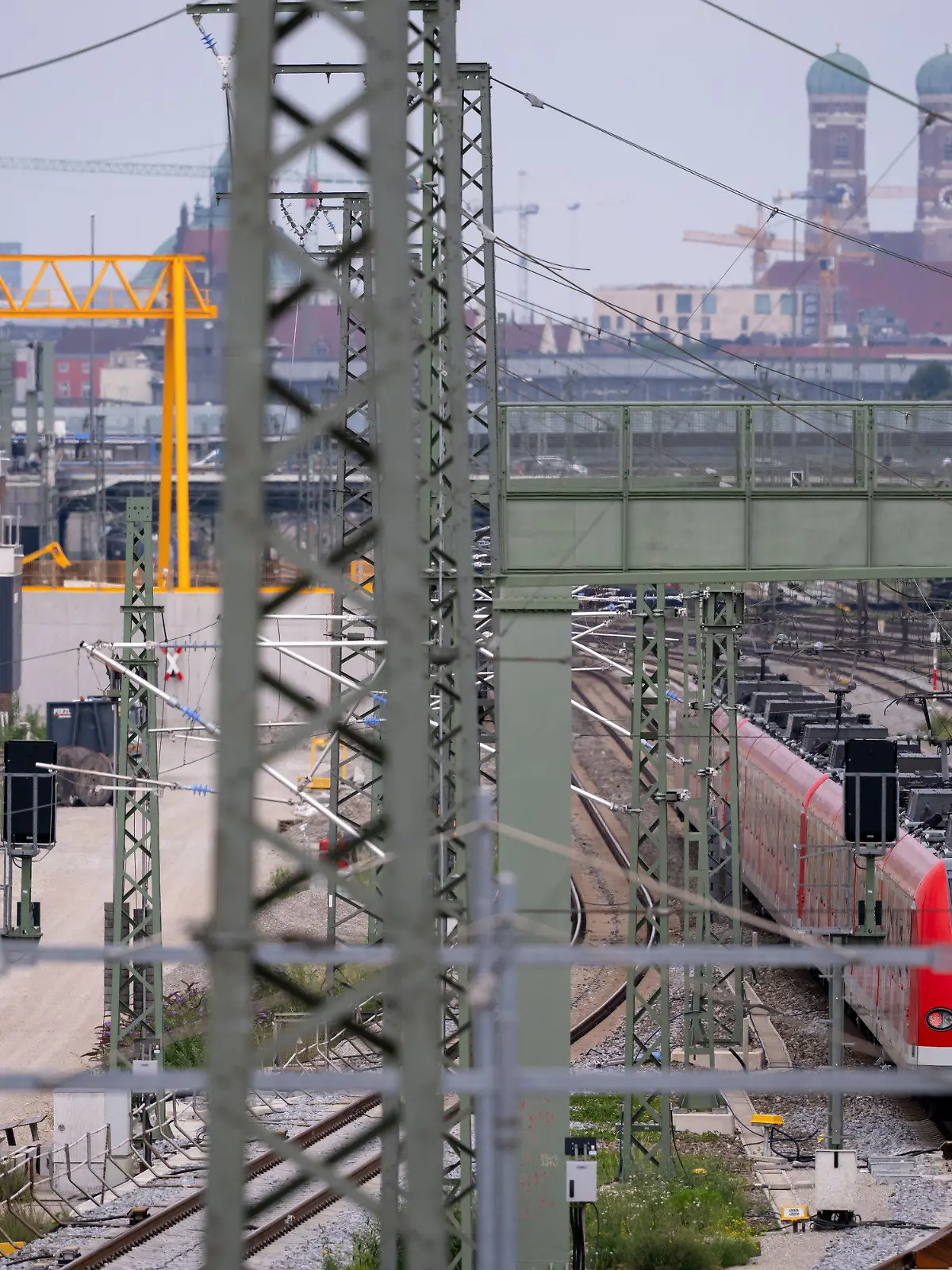ARCHIV - 21.07.2022, Bayern, München: Ein Zug der S-Bahn München fährt an der Baustelle der zweiten S-Bahn-Stammstrecke entlang. Was nach Industrieromantik aussieht mit den Türmen der Münchner Frauenkirche im Hintergrund sorgt für heftige Debatten wegen massiver Kostensteigerungen und jahrelanger Verzögerungen. Nun hofft man in München, dass die Deutsche Bahn endlich konkrete Zahlen und Daten nennt. (zu dpa «Hoffen auf konkrete Zahlen: Die zweite S-Bahn-Stammstrecke in München») Foto: Sven Hoppe/dpa +++ dpa-Bildfunk +++