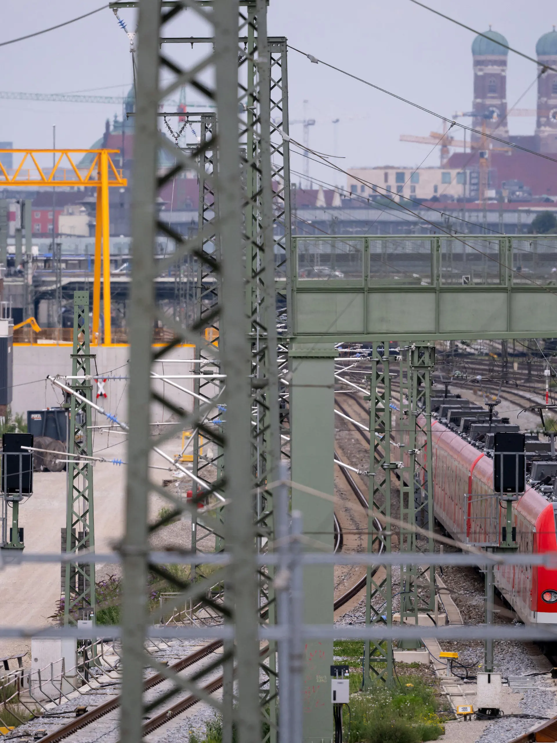 ARCHIV - 21.07.2022, Bayern, München: Ein Zug der S-Bahn München fährt an der Baustelle der zweiten S-Bahn-Stammstrecke entlang. Was nach Industrieromantik aussieht mit den Türmen der Münchner Frauenkirche im Hintergrund sorgt für heftige Debatten wegen massiver Kostensteigerungen und jahrelanger Verzögerungen. Nun hofft man in München, dass die Deutsche Bahn endlich konkrete Zahlen und Daten nennt. (zu dpa «Hoffen auf konkrete Zahlen: Die zweite S-Bahn-Stammstrecke in München») Foto: Sven Hoppe/dpa +++ dpa-Bildfunk +++