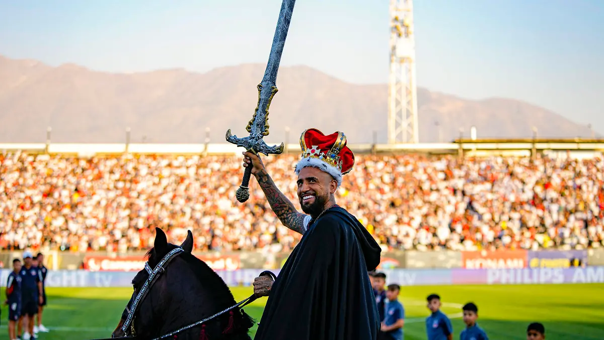 Chilean soccer player Arturo Vidal waves a sword while riding a horse on to the pitch at his welcoming event at the Monumental Stadium in Santiago, Chile, Thursday, Feb. 1, 2024. Vidal returns to play for Colo Colo after 17 years of a successful career playing for soccers clubs in Europe and South America. (AP Photo/Esteban Felix)