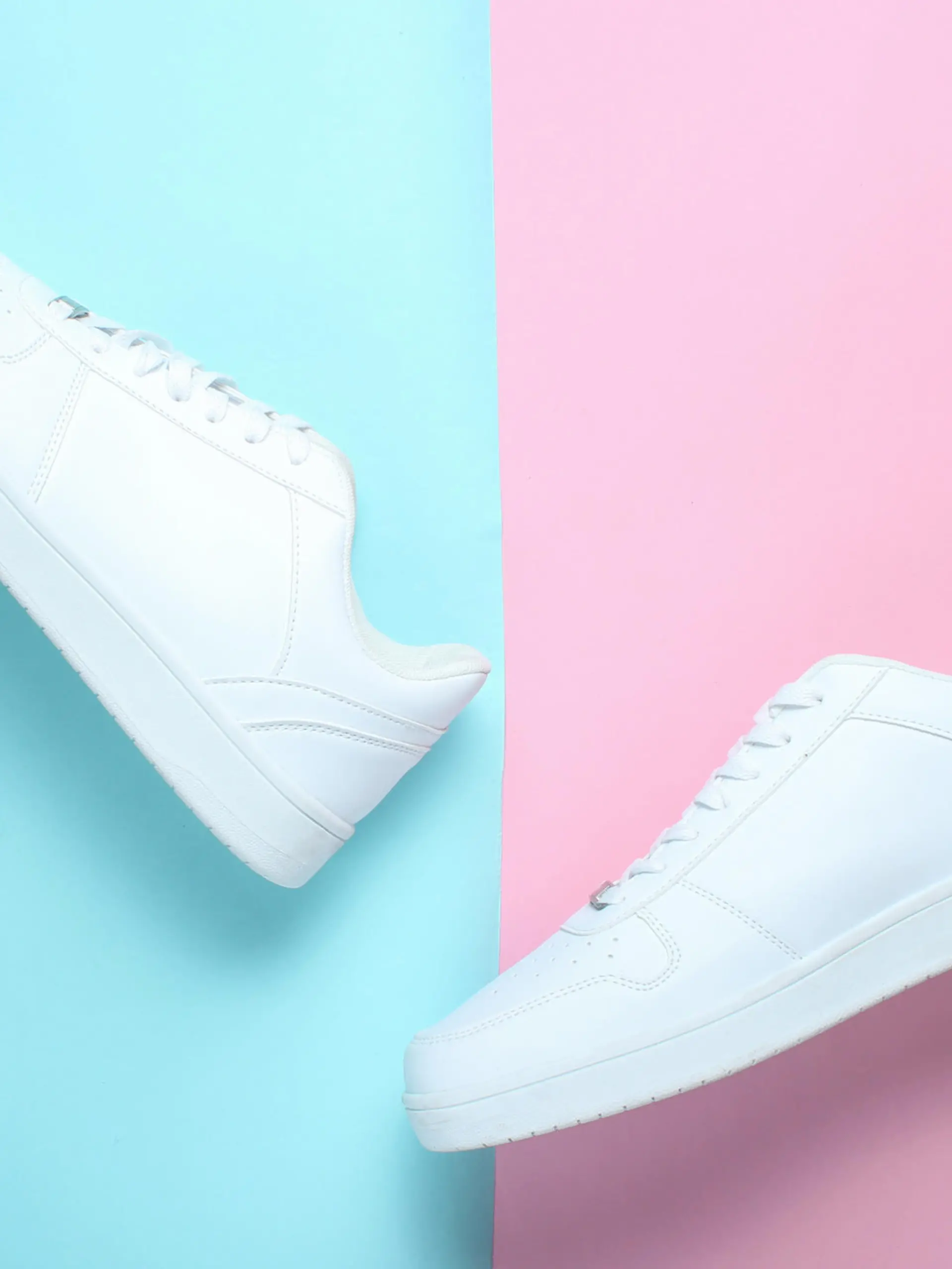 Weiße Sneaker vor pinkem und blauem Hintegrund.