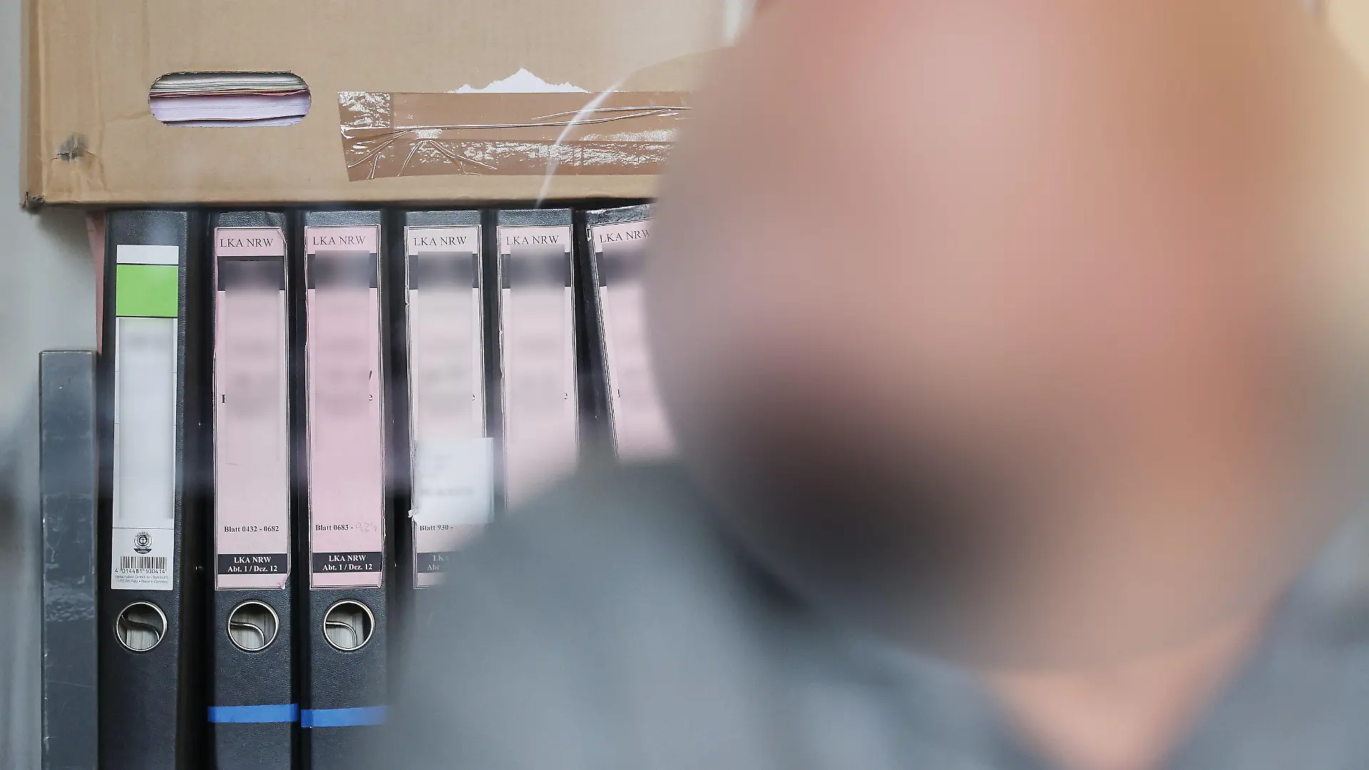 20.07.2023, Nordrhein-Westfalen, Duisburg: Der Angeklagte sitzt im Duisburger Landgericht bei seinem Prozess vor seinen Gerichtsakten. In Duisburg hat ein Strafprozess gegen den früheren Vorstandsvorsitzenden eines Vereins begonnen, der fast 700.000 Euro für private Reisen und Luxusgüter veruntreut haben soll. Foto: David Young/dpa - ACHTUNG: die Person wurde aus rechtlichen Gründen gepixelt +++ dpa-Bildfunk +++