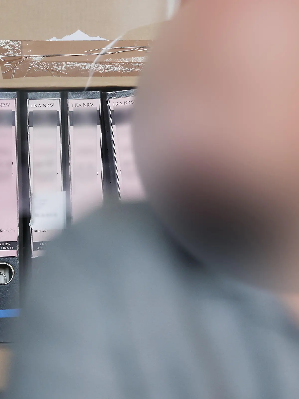 20.07.2023, Nordrhein-Westfalen, Duisburg: Der Angeklagte sitzt im Duisburger Landgericht bei seinem Prozess vor seinen Gerichtsakten. In Duisburg hat ein Strafprozess gegen den früheren Vorstandsvorsitzenden eines Vereins begonnen, der fast 700.000 Euro für private Reisen und Luxusgüter veruntreut haben soll. Foto: David Young/dpa - ACHTUNG: die Person wurde aus rechtlichen Gründen gepixelt +++ dpa-Bildfunk +++