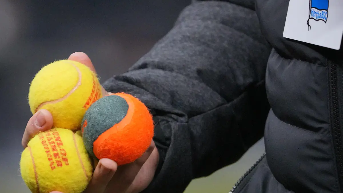 03.02.2024, Berlin: Fußball: 2. Bundesliga, Hertha BSC - Hamburger SV, 20. Spieltag, Olympiastadion. Ein Ordner hat drei Tennisbälle aufgesammelt, die von Hertha-Fans aufs Spielfeld geworfen worden waren. Foto: Soeren Stache/dpa - WICHTIGER HINWEIS: Gemäß den Vorgaben der DFL Deutsche Fußball Liga bzw. des DFB Deutscher Fußball-Bund ist es untersagt, in dem Stadion und/oder vom Spiel angefertigte Fotoaufnahmen in Form von Sequenzbildern und/oder videoähnlichen Fotostrecken zu verwerten bzw. verwerten zu lassen. +++ dpa-Bildfunk +++