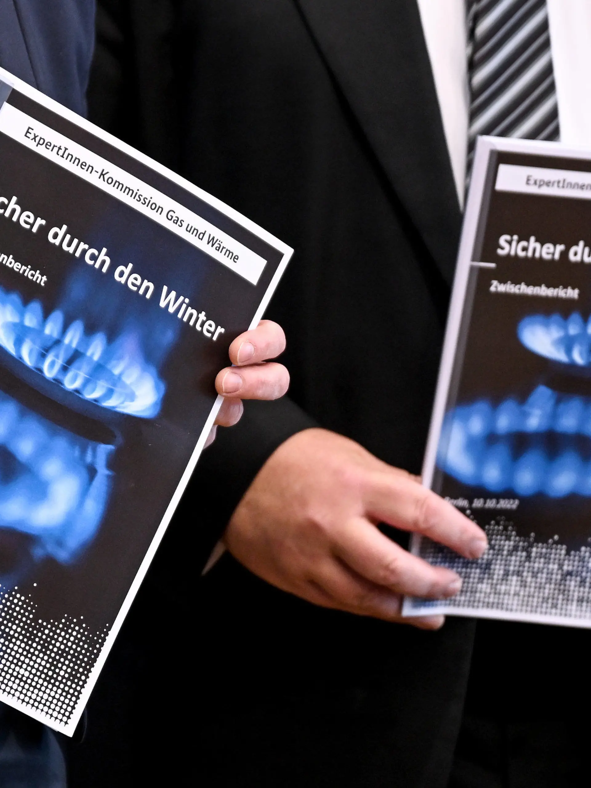 10.10.2022, Berlin: Teilnehmer der Pressekonferenz zum Zwischenbericht der Kommission Erdgas und Wärme halten den Bericht in ihren Händen. Die Ampelkoalition hat angekündigt, Verbraucher und Unternehmen wegen der steigenden Energiepreise zu unterstützen. Foto: Britta Pedersen/dpa +++ dpa-Bildfunk +++