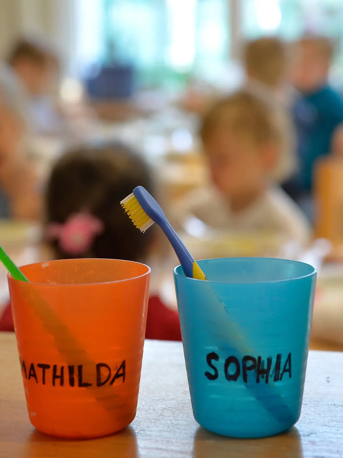 ARCHIV - ILLUSTRATION - 18.04.2016, Nordrhein-Westfalen, Düsseldorf: Zahnbürsten und Zahnputzbecher mit den Vornamen der Kinder stehen in einer Kindertagesstätte auf einem Tisch. Neuköllns Bezirksbürgermeister Martin Hikel fordert eine Kita-Pflicht für alle Kinder. (zu "Neuköllner Bezirksbürgermeister plädiert für Kita-Pflicht" vom 28.07.2018) Foto: Monika Skolimowska/dpa +++ dpa-Bildfunk +++