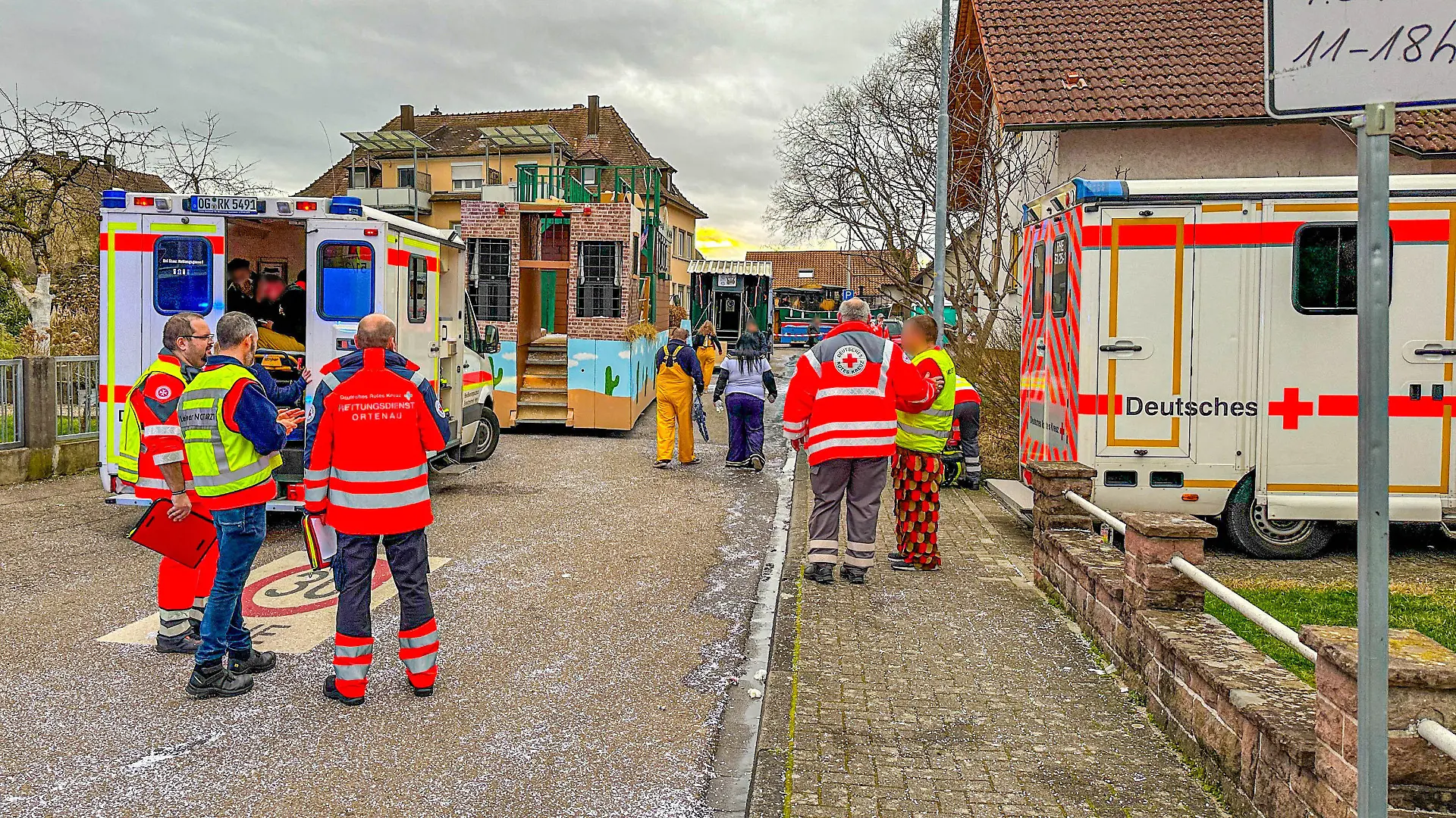 04.02.2024, Baden-Württemberg, Kehl: Rettungswagen, Karnevalisten und Einsatzkräfte stehen in der Nähe der Unfallstelle. Bei einem Faschingsumzug im baden-württembergischen Kehl ist am Sonntag ein Faschingswagen in Brand geraten. Foto: Marco Dürr/Einsatzreport24/dpa +++ dpa-Bildfunk +++
