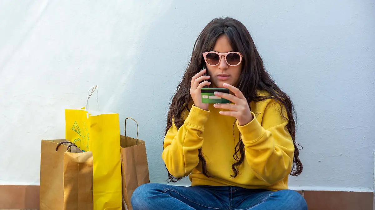 young girl holding a credit card and using a smartphone to make a purchase. Online shopping concept