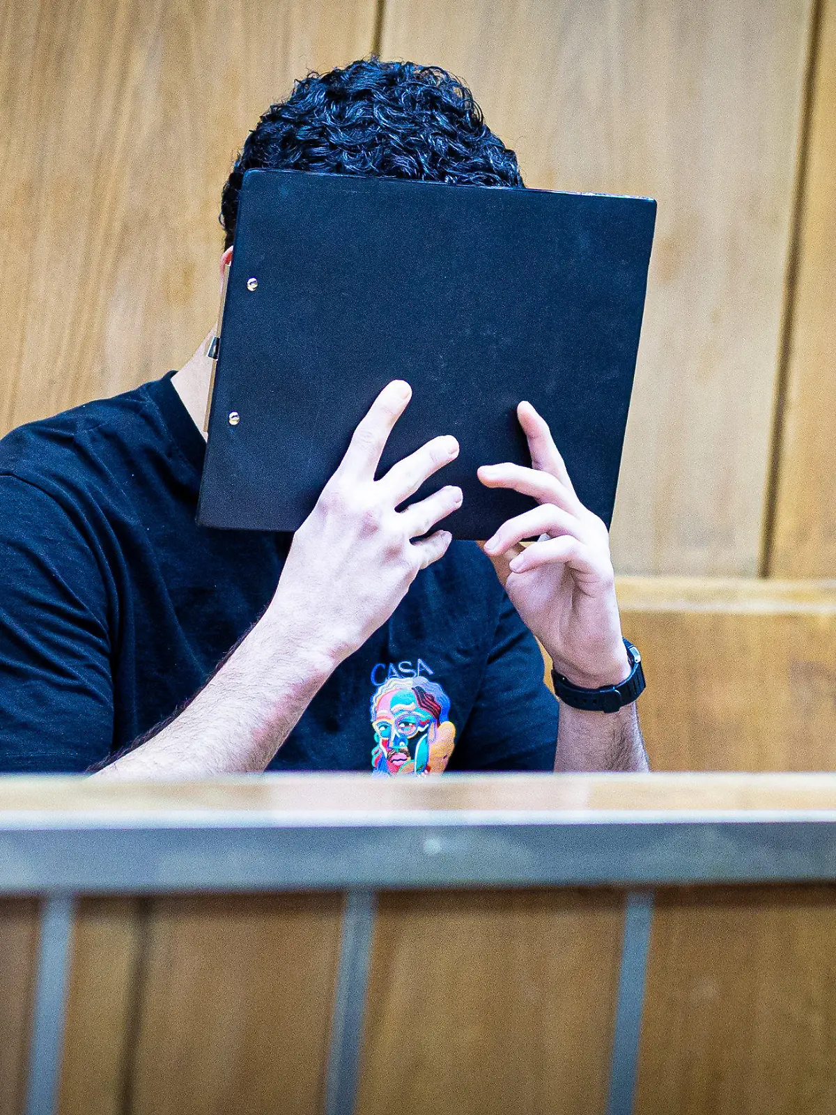 05.02.2024, Niedersachsen, Hannover: Der Angeklagte verdeckt sein Gesicht mit einer Mappe bei Prozessauftakt in einem Saal im Landgericht Hannover. Dem Angeklagten wird vorgeworfen, im Juli 2023 in Hannover zusammen mit einer weiteren Person einen Juwelier überfallen zu haben. Foto: Moritz Frankenberg/dpa +++ dpa-Bildfunk +++