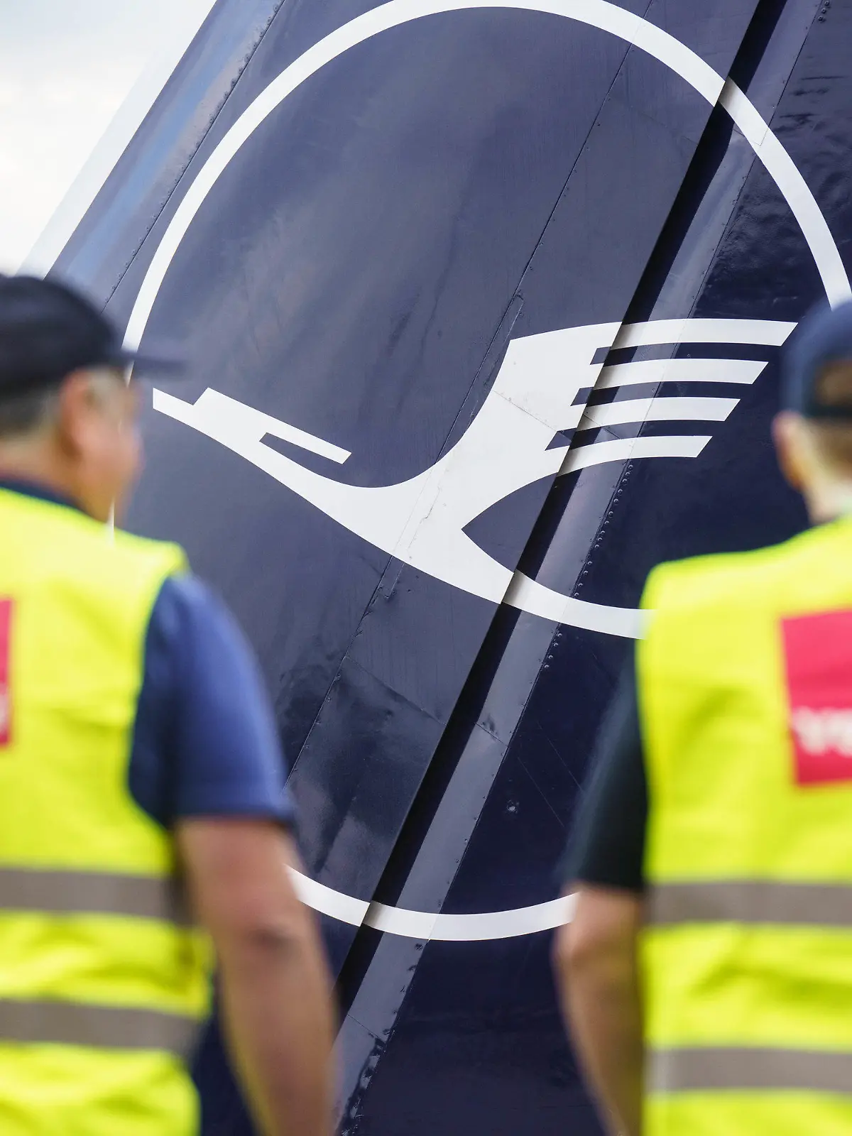 ARCHIV - 27.07.2022, Hessen, Frankfurt/Main: Zwei Verdi-Mitglieder stehen am Morgen am Frankfurter Flughafen am Eingang zur Lufthansa-Basis. An diesem Mittwoch tritt das Bodenpersonal mehrerer Lufthansa-Gesellschaften in den Warnstreik. (zu dpa: «Verdi zwingt Lufthansa zu Rumpf-Programm») Foto: Frank Rumpenhorst/dpa +++ dpa-Bildfunk +++