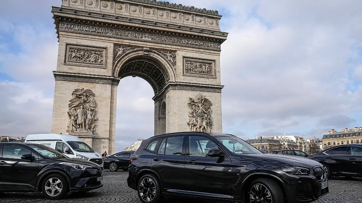 SUVs fahren auf der Champs Elysee vor dem Arc de Triomphe.
