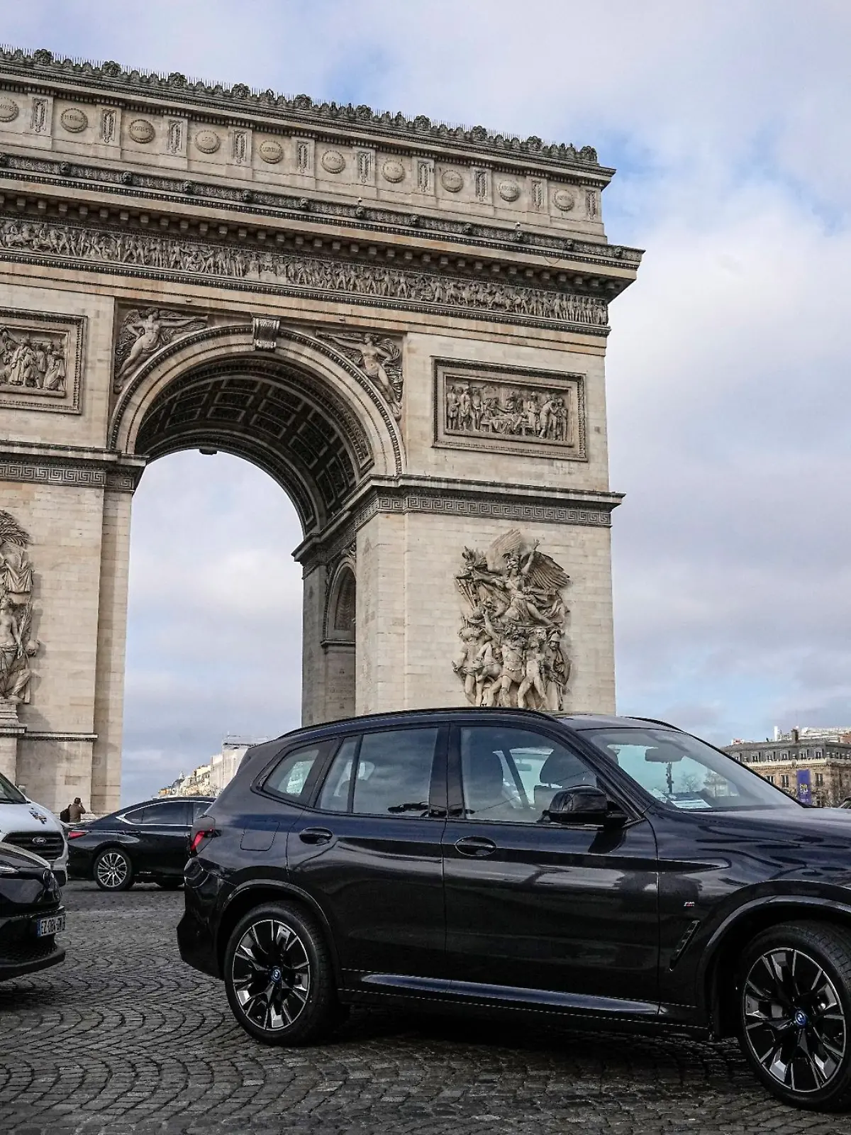 SUVs fahren auf der Champs Elysee vor dem Arc de Triomphe.