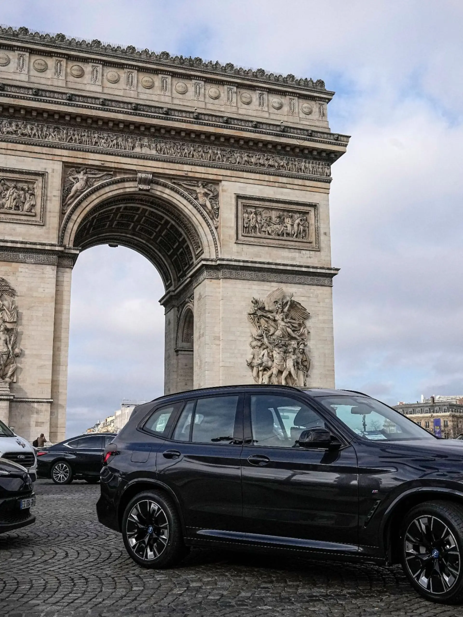 SUVs fahren auf der Champs Elysee vor dem Arc de Triomphe.