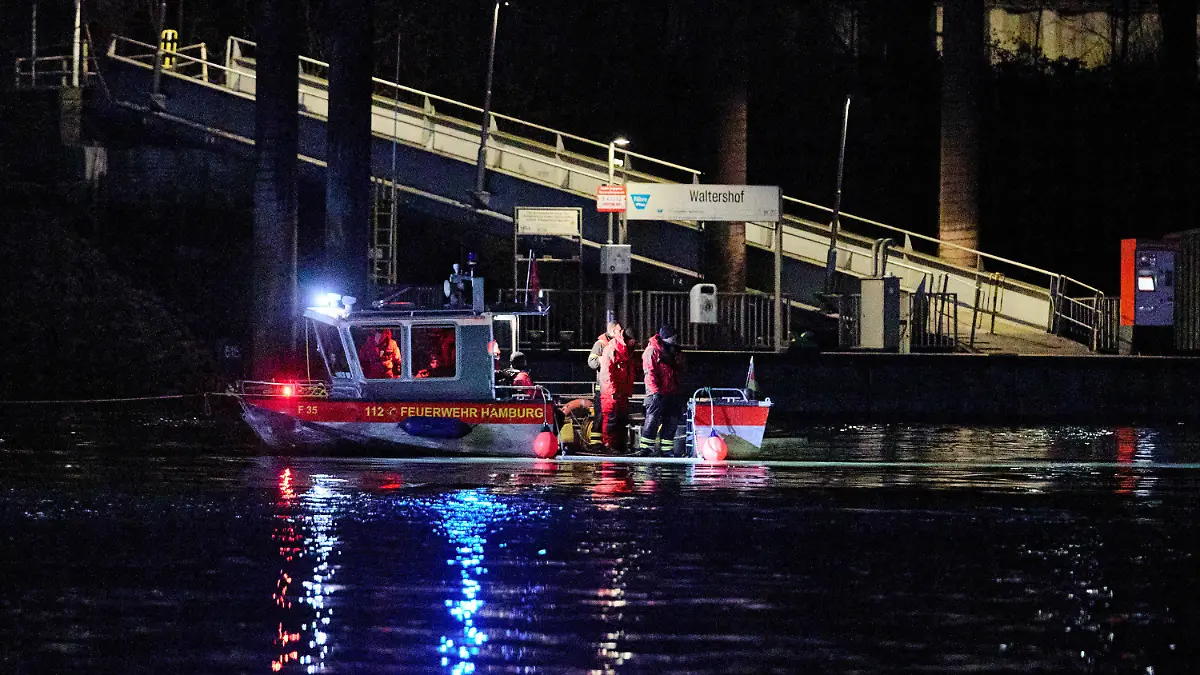 07.02.2024, Hamburg: Feuerwehrleute stehen in der Nähe des Anlegers Waltershof auf einem Boot. In der Hamburger Elbe suchen Taucher derzeit in der Nähe der Köhlbrandbrücke nach einem vermissten Menschen, sagte ein Sprecher der Feuerwehr. Ein sogenanntes Festmacherboot sei nach dem Zusammenstoß mit einem Schubverband gesunken. Foto: Georg Wendt/dpa +++ dpa-Bildfunk +++