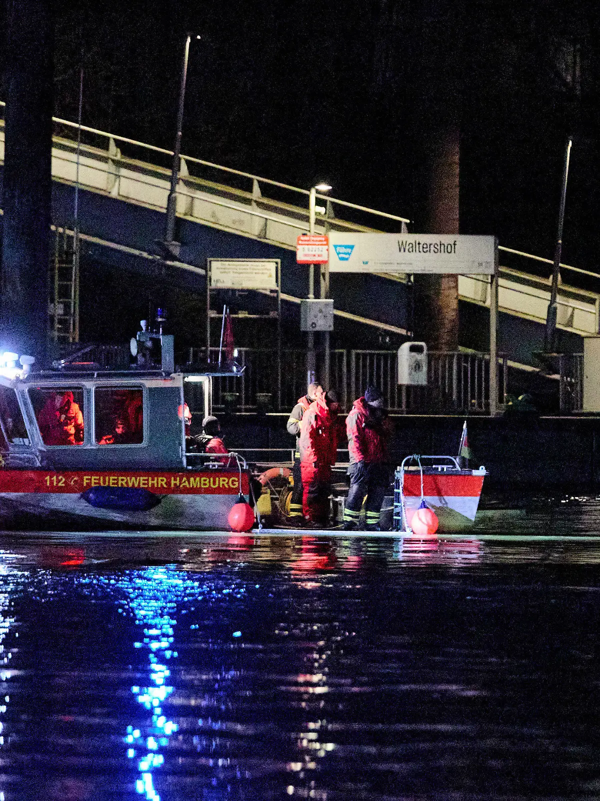 07.02.2024, Hamburg: Feuerwehrleute stehen in der Nähe des Anlegers Waltershof auf einem Boot. In der Hamburger Elbe suchen Taucher derzeit in der Nähe der Köhlbrandbrücke nach einem vermissten Menschen, sagte ein Sprecher der Feuerwehr. Ein sogenanntes Festmacherboot sei nach dem Zusammenstoß mit einem Schubverband gesunken. Foto: Georg Wendt/dpa +++ dpa-Bildfunk +++