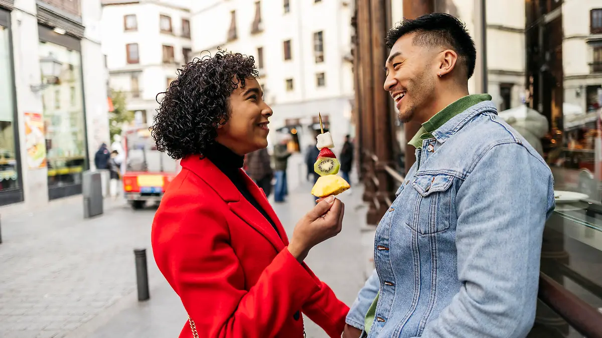 young couples in a relationship on the city street enjoying a fruit dessert on their Valentine's date.