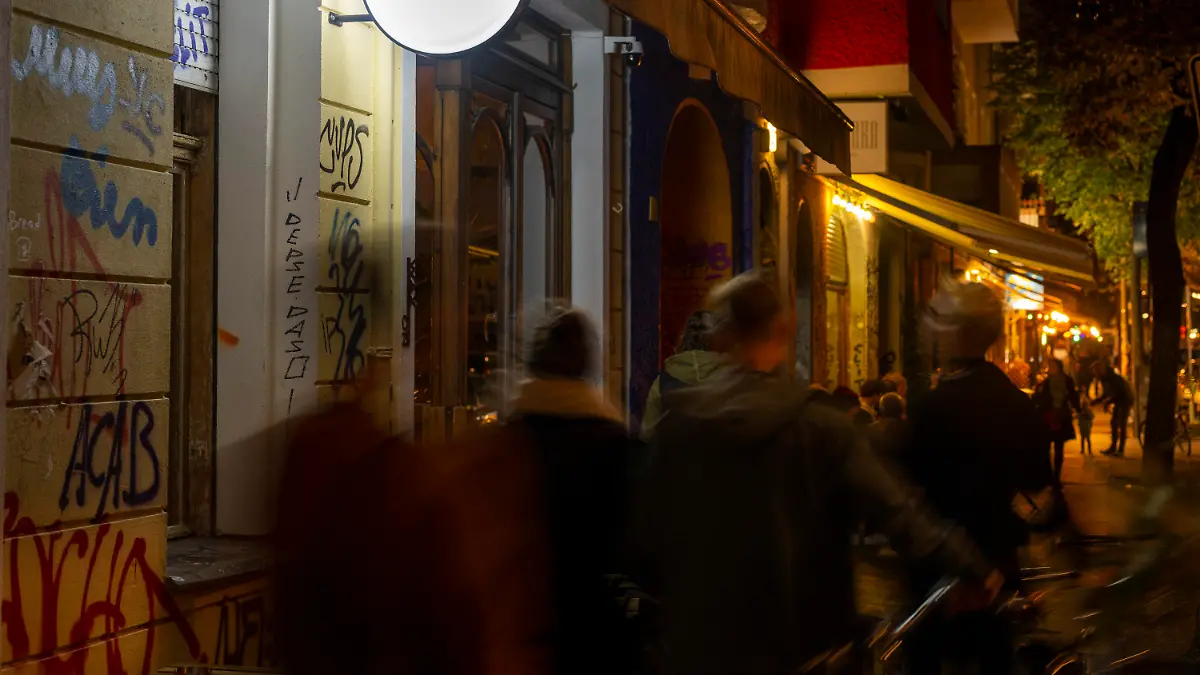PRODUKTION - 07.10.2022, Berlin: Passanten gehen am Abend vorbei an der Neuköllner Bar "Wax On". Ausgeh-Locations in Berlin, Wien, Zürich, Frankfurt und München gehören zu den Siegern bei den Mixology Bar Awards für das kommende Jahr 2023. Als «Neue Bar des Jahres» wurde das «Wax On» in Berlin ausgezeichnet. (Zu dpa: "Bars des Jahres 2023 sind in Berlin, Wien, Zürich") Foto: Monika Skolimowska/dpa +++ dpa-Bildfunk +++
