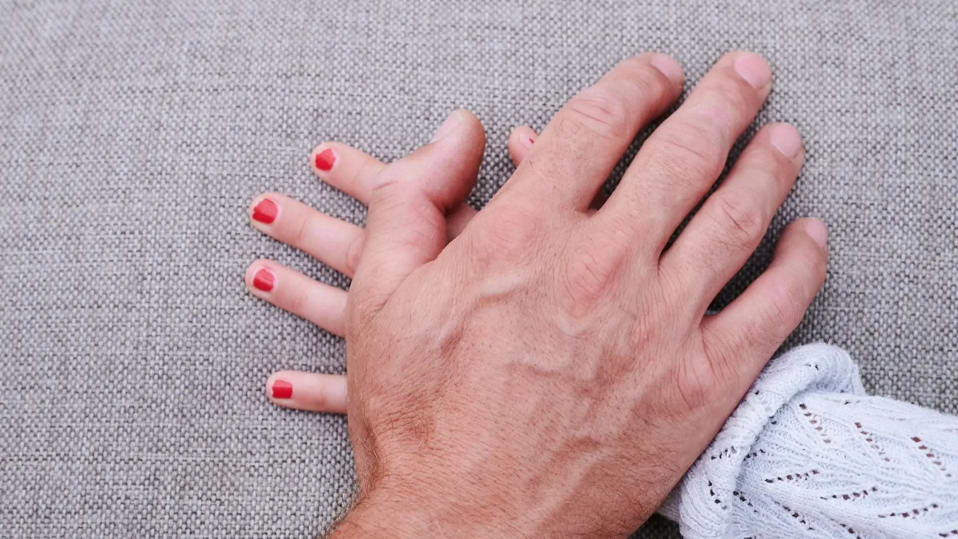 Eine Männerhand liegt auf einer Mädchenhand. (gestellte Szene).
