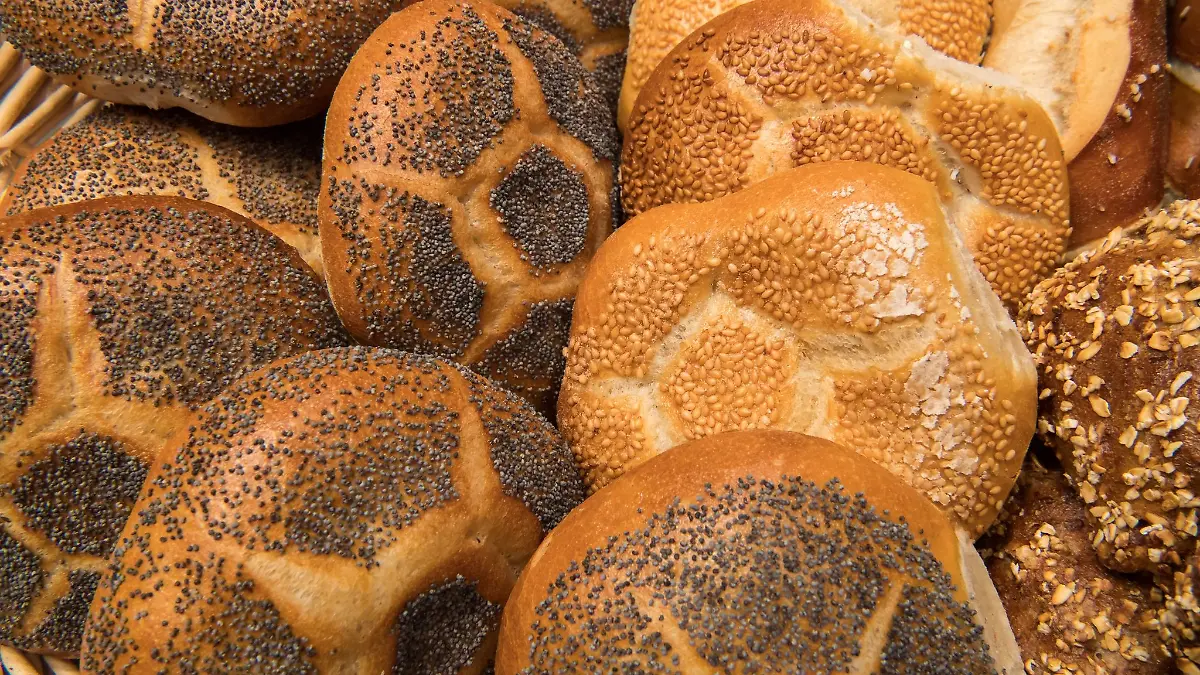 Verschiedene Semmeln liegen in der Auslage einer Bäckerei in einem Korb in der Auslage.