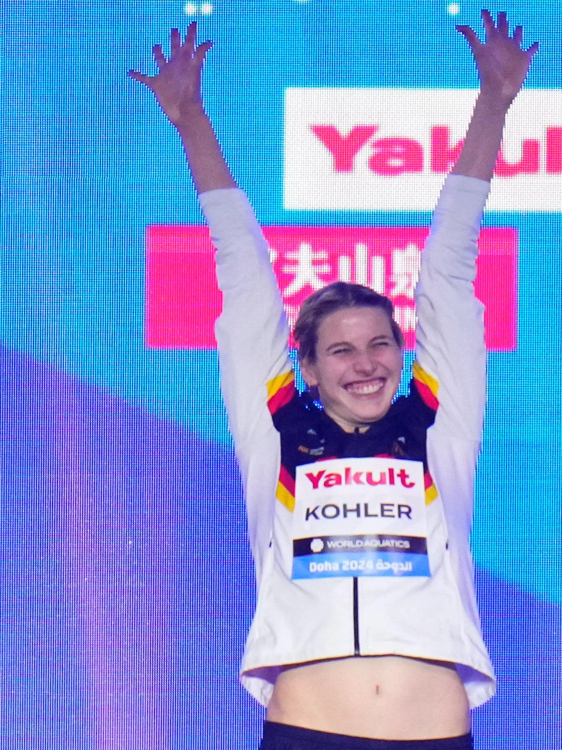 12.02.2024, Katar, Doha: Schwimmen: Weltmeisterschaft, 100 m Schmetterling, Frauen, Finale: Angelina Köhler aus Deutschland jubelt auf dem Podium über ihren Sieg. Foto: Hassan Ammar/AP/dpa +++ dpa-Bildfunk +++