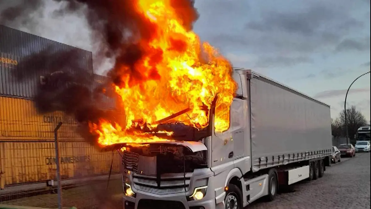 12.02.2024, Hamburg, Hambühren: Ein brennender LKW steht neben Containern am Straßenrand. In einem brennenden Lkw am Hamburger Hafen haben Einsatzkräfte einen toten Menschen im Fahrerhaus gefunden. Das Fahrerhaus des 40-Tonners im Stadtteil Kleine Grasbrook habe am späten Montagnachmittag in voller Ausdehnung gebrannt, teilte ein Polizeisprecher mit. Nach dem Löschen des Sattelzugs habe man die verstorbene Person dort entdeckt. Die Brandursache war laut dem Sprecher unklar. Feuerwehr und Kriminalpolizei waren demnach am Abend noch vor Ort. Foto: -/TV7News/dpa +++ dpa-Bildfunk +++